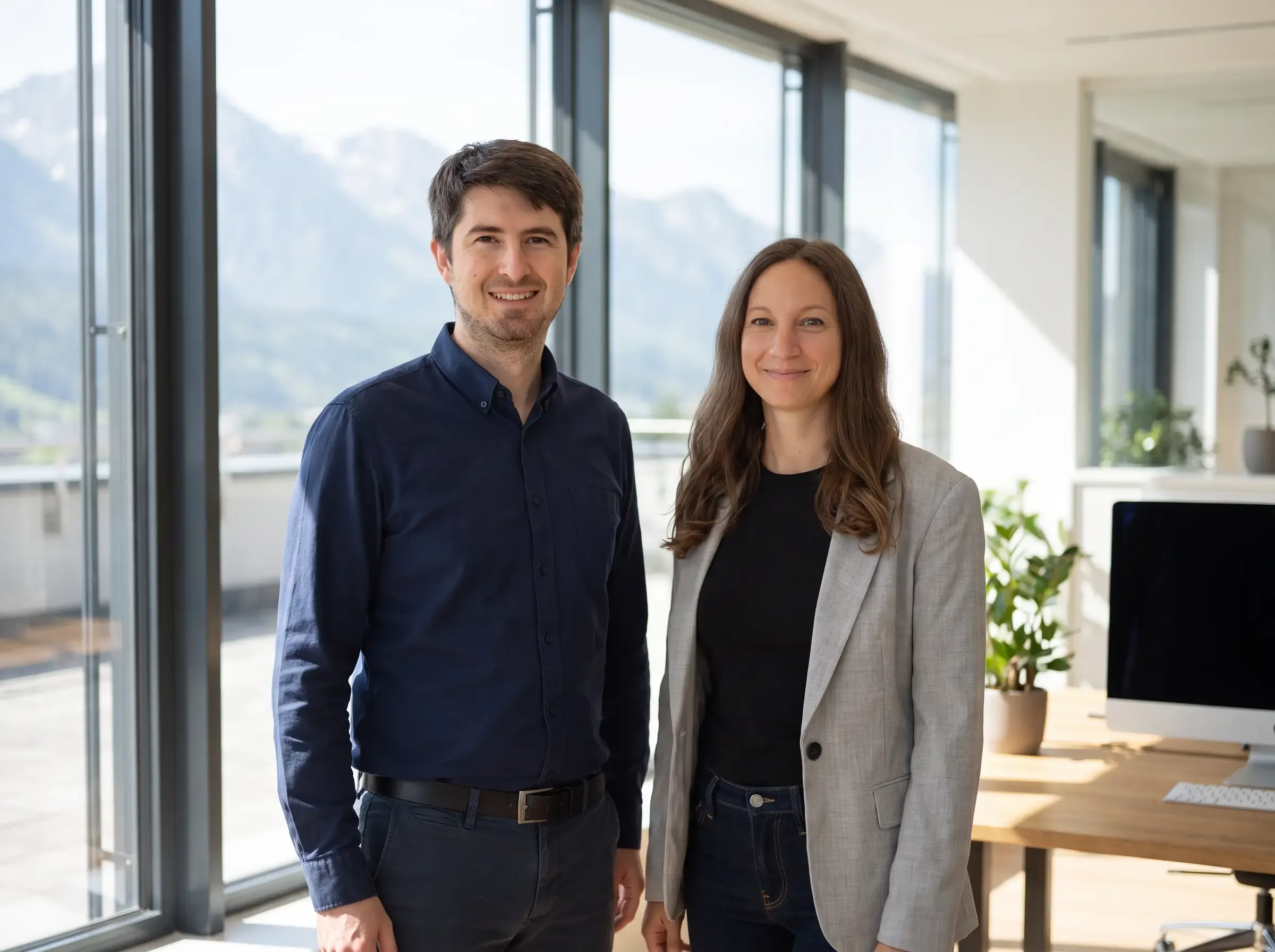 Nadine und Christoph Fraiss, die Gründer von Lilox, nebeneinander in einem hellen Büro, im Hintergrund Berge